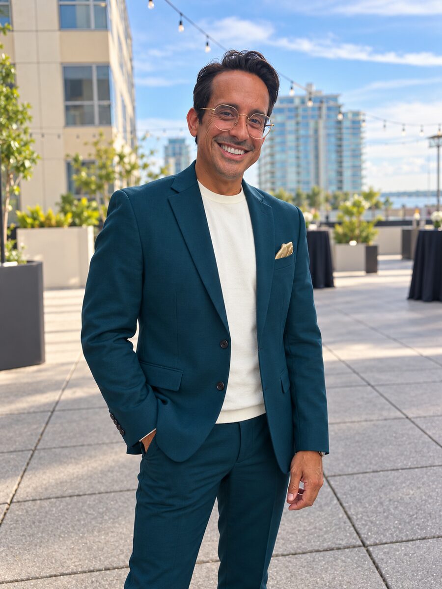 Hector Negroni, travel advisor, smiling on a city rooftop in a teal suit