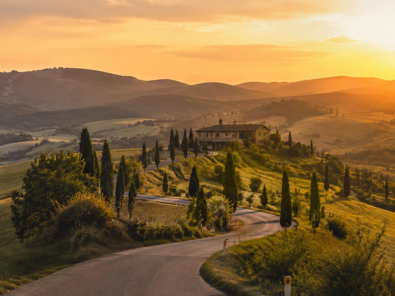 A winding road through golden hills toward a stone villa